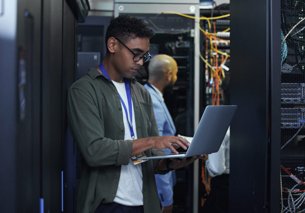 IT work in progress. Cropped shot of two male IT support agents working together in a dark network server room. IT projects